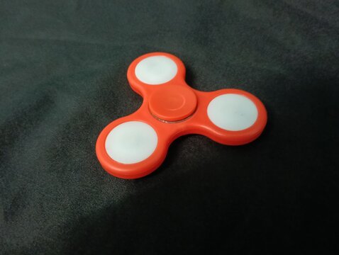 A red fidget spinner is a small toy designed to be spun between the fingers. It became very popular for stress relief and as a tool to aid focus, especially for individuals with anxiety, ADHD, or auti - Powered by Adobe