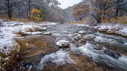 Snowy river flows through a forest after a snowfall; rocks and trees are dusted with white