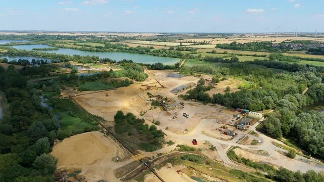 Aerial drone perspective of a quarry mining area with heavy machinery and aggregates minerals extraction in rural landscape near Little Paxton England UK