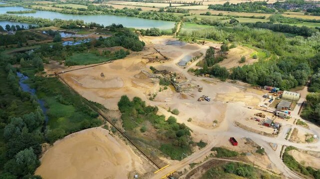 Aerial drone perspective of a quarry mining area with heavy machinery and aggregates minerals extraction in rural landscape near Little Paxton England UK