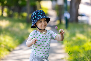 Young Boy Holding Flowers on Sunny Day in Park Setting