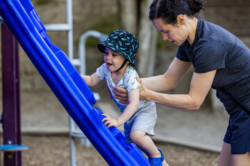 Mother Helping Toddler On Playground Slide Outdoor Activity in Vancouver