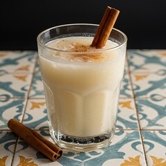  Refreshing glass of Mexican Aguas Frescas, specifically Horchata (rice drink) with cinnamon stick, condensation on the glass, on a vibrant patterned tile,