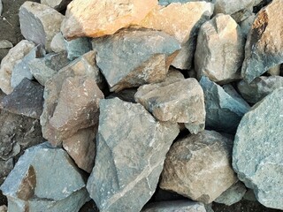 There is a pile of large, broken, and irregularly shaped rocks. The surface texture of the rocks is rough and uneven, and they are typically used for building foundations.