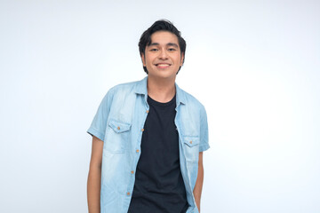 Confident Southeast Asian Gen Z man in blue polo and black shirt stands smiling with upbeat relaxed...