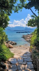 Fototapeta premium Serene Coastal Pathway Leading to Tranquil Blue Sea and Mountains