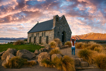 Woman making the heart symbol on the grounds of the Tekapo Chapel