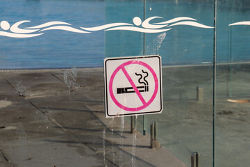 no smoking sign on glass swimming pool fence