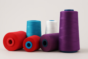 Colorful spools of thread are arranged on a white background
