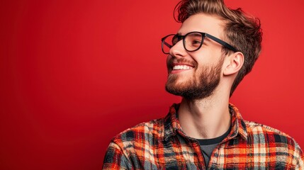 Obraz premium Cheerful young man in plaid shirt against vibrant red backdrop