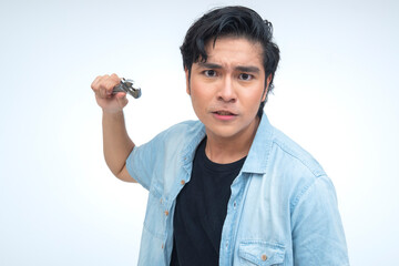 Young Southeast Asian man looking mad and furious, aggressively holding an adjustable wrench in a...