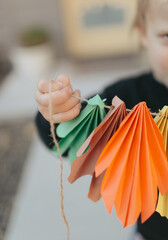 Toddler playing with colorful paper garland for halloween party decoration