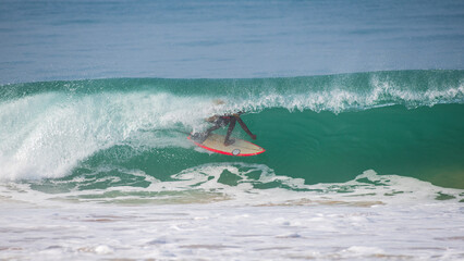 Surfer rides deep inside a powerful, glassy barrel, showcasing skill and control on a vibrant...