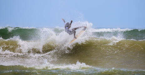 Young surfer boy in action on the beautiful beach in Weligama Bay.