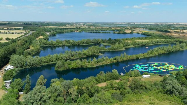 Aerial drone shot beautiful blue lakes and lush greenery with aqua water park play event near Little Paxton England UK