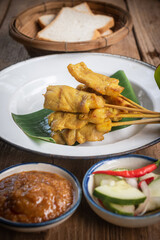 satay skewers with grilled pork and dipping sauces served on banana leaf plate