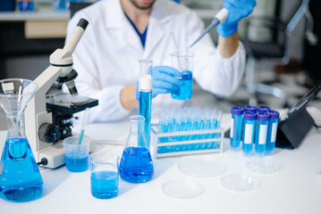 male scientist working with micro pipettes analyzing biochemical samples, advanced science chemical...