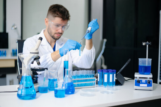 scientists in lab coats conducting research, handling glassware, and working with chemicals