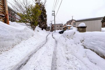 雪国の生活道路。自動車のタイヤが作るわだちで生活道路は歩行が大変