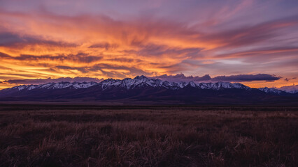 A gorgeous panorama of autumn mountains and yellow grass shines in the evening sunlight.