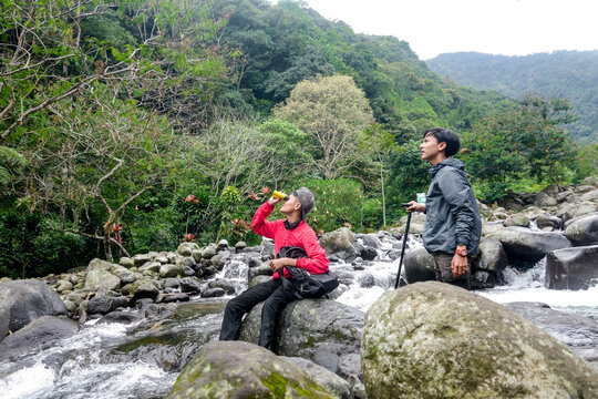 Adventurers Taking A Refreshing Break By Flowing Stream