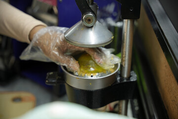 Close-up of hands cutting fresh oranges to be squeezed into juice and sold. Local Indonesian...