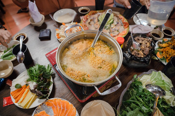 Vietnamese hot pot is simmered with noodles, vegetables and broth, surrounded by fresh herbs,...