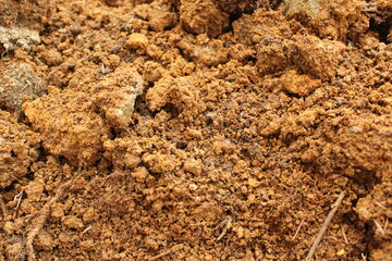 high angle close up of rough, reddish-brown soil with visible clumps and loose grains, ideal for gardening or natural backgrounds