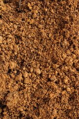 high angle close up of rough, reddish-brown soil with visible clumps and loose grains, ideal for gardening or natural backgrounds
