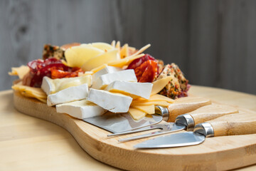 Food trend gift aperitivo party idea. Appetizers wooden grazing board with different antipasti charcuterie snacks and cheese. Assorted cheese meat platter. Disordered eating. Girl dinner