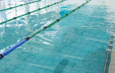 Floating lane dividers are crossing turquoise lap pool water over grid-pattern floor in flat design
