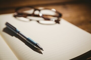 Obraz premium Eyeglasses and pen on book