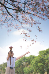 asian woman relax and happy with see pink cherry blossom in spring season