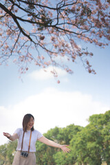 asian woman relax and happy with see pink cherry blossom in spring season