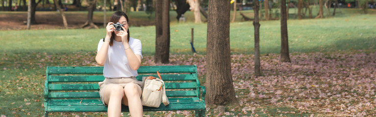 asian woman solo traveler relax and enjoy to see and take photo pink cherry blossom blooming from springtime road trip