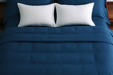 Cozy bed with two pillows and navy blue bedding