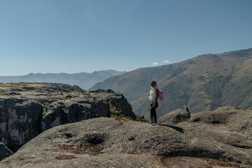 Persona posando en la meseta de la montaña de Marcahuasi con una laguna delante de él mirando el...