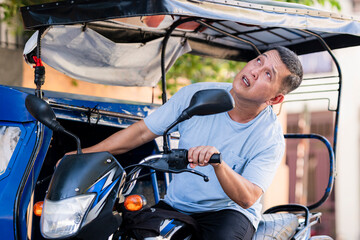 The tricycle driver looks at the sky, checking for signs of rain with a slightly anxious, uncertain expression while on his vehicle.