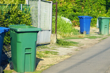 Individual garbage bins, blue and green, standing on the side of the road. Municipal waste...