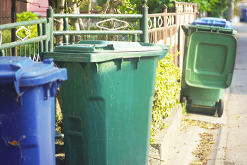Blue and green garbage bins on sidewalk. Symbol of modern waste sorting and recycling. Concepts of...