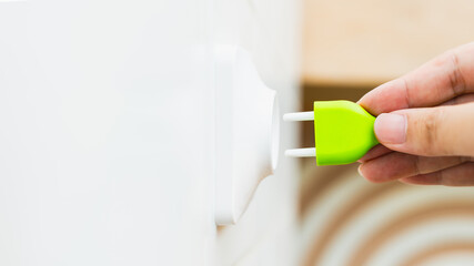Businessman holding a green plug plugged into a socket, concept of carbon credit, using natural...