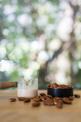 Glass fresh milk and many of Almonds nut in small bowl on wooden table with copy space