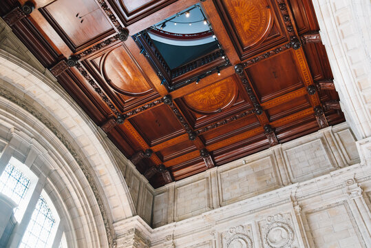 The intricately carved wooden ceiling showcases exquisite craftsmanship, featuring a design typical of the Renaissance or Victorian Revival styles, commonly found in museums or grand halls throughout.