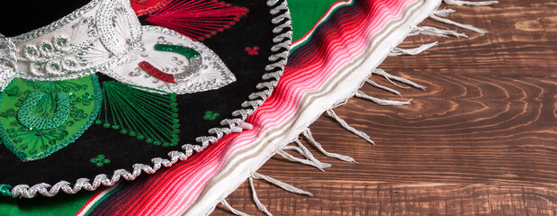 Serape and Mexican hat on wooden table. Mexican background. Banner