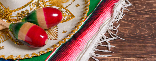 Maracas, serape and Mexican hat on wooden table. Mexican background. Banner