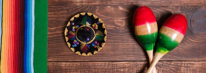 Maracas, serape and Mexican hat on wooden table. Mexican background. Banner