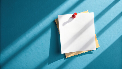 Clean minimalist overhead shot of white note pinned on textured background, casting shadows