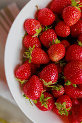 Fresh sweet strawberries in a white bowl on a white background. Seasonal berries.