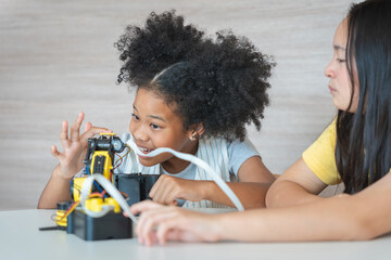 Young Girls Engaged in Robotics and STEM Learning, Diverse Kids Building a Robot Arm in a Science Workshop, Two Girls Exploring Technology and Innovation