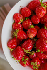 Fresh sweet strawberries in a white bowl on a white background. Seasonal berries.